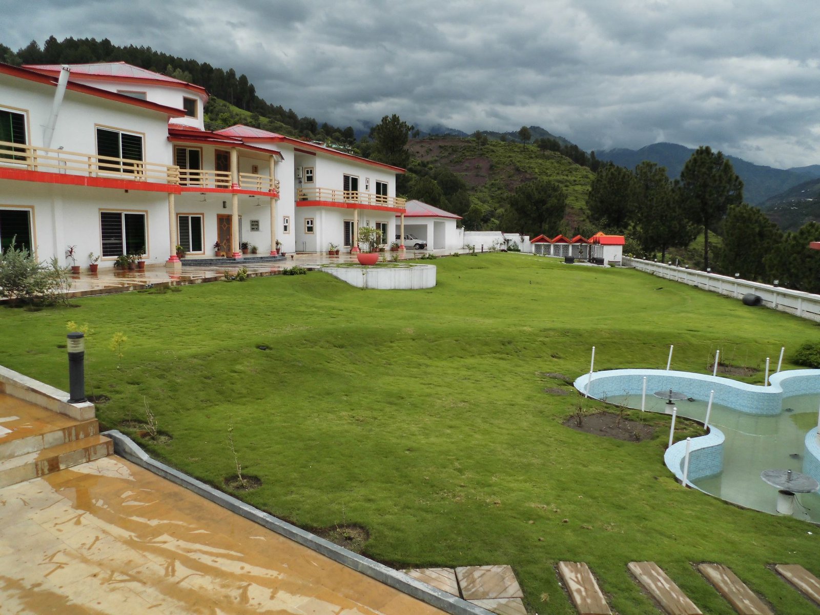 Highland Lodges Balakot exterior with lawn, kids pool and mountain backdrop