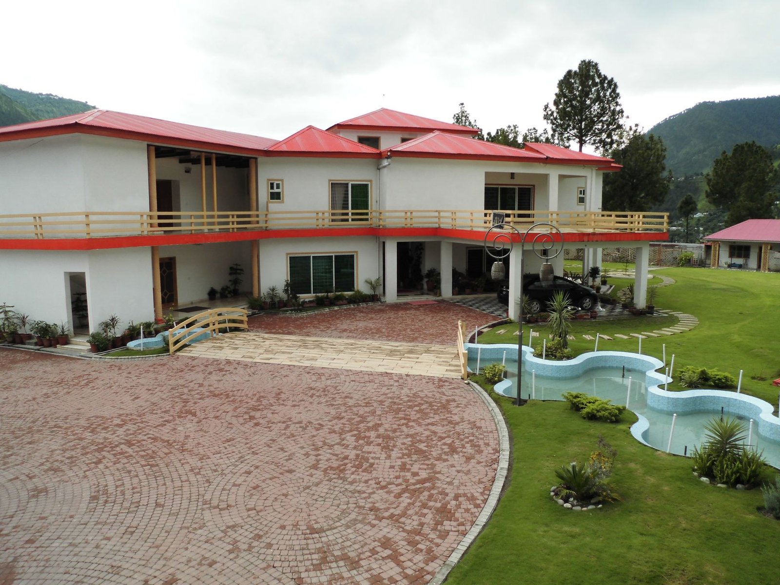 Lodge facade, driveway and kidney-shaped kids pool